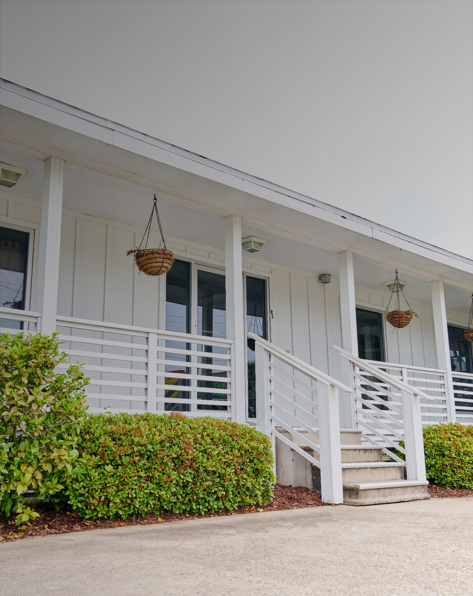 Maintained home exterior with trimmed hedges and hanging planters in Metairie, LA